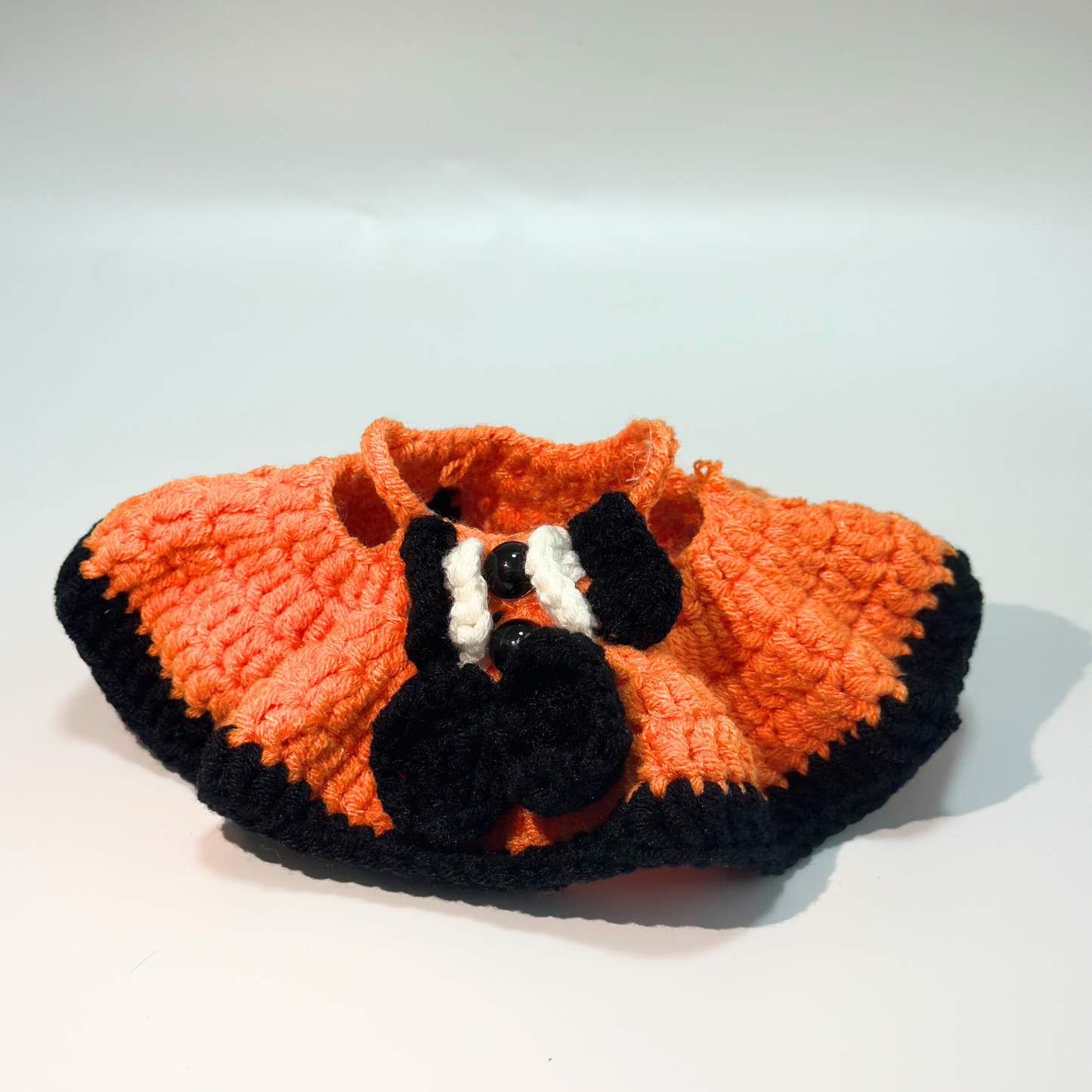 Interior view of handmade crocheted Halloween witch dress for Labubu doll showing orange textured fabric with ribbed pattern, black trim details, and quality construction. Displays craftsmanship and functional design elements of Halloween doll costume, perfect collectible seasonal outfit for toy enthusiasts.