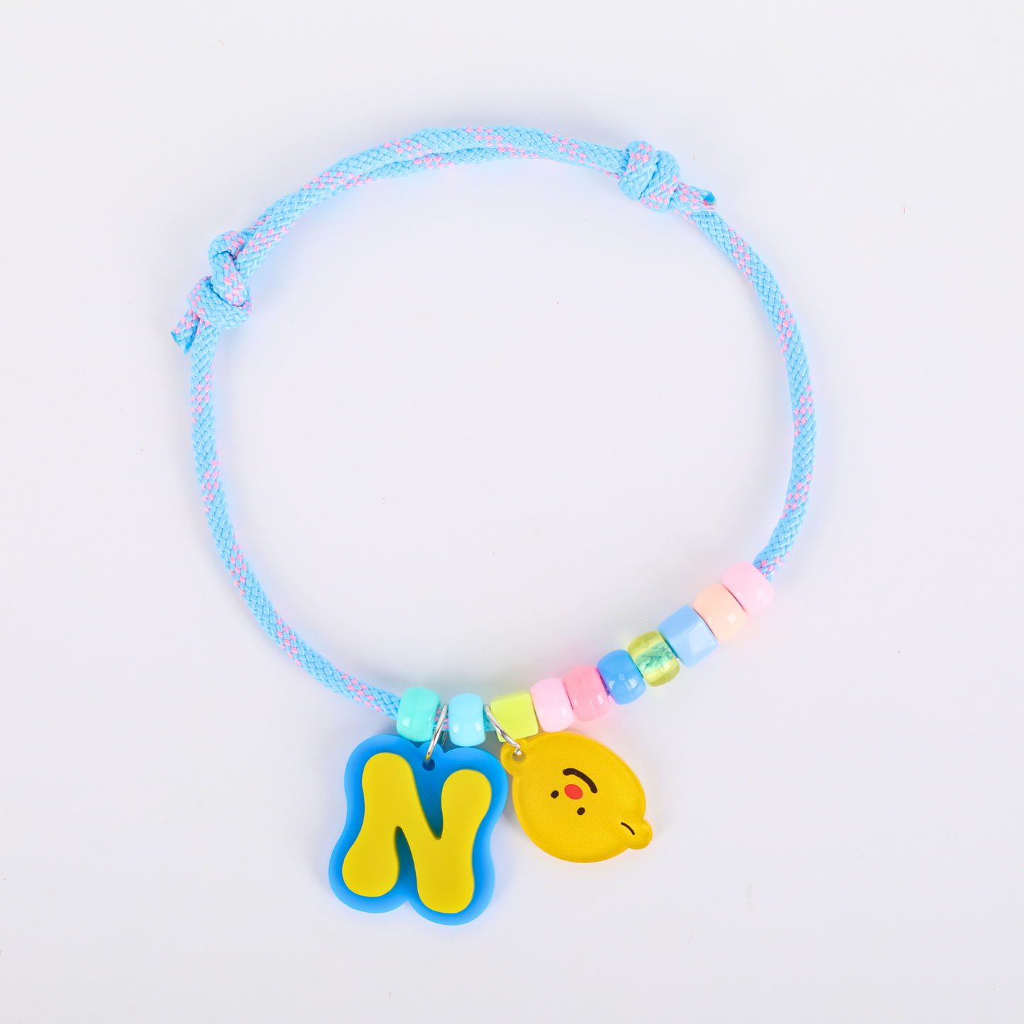 Colorful pet necklace with a blue cord and yellow charms on a light gray background