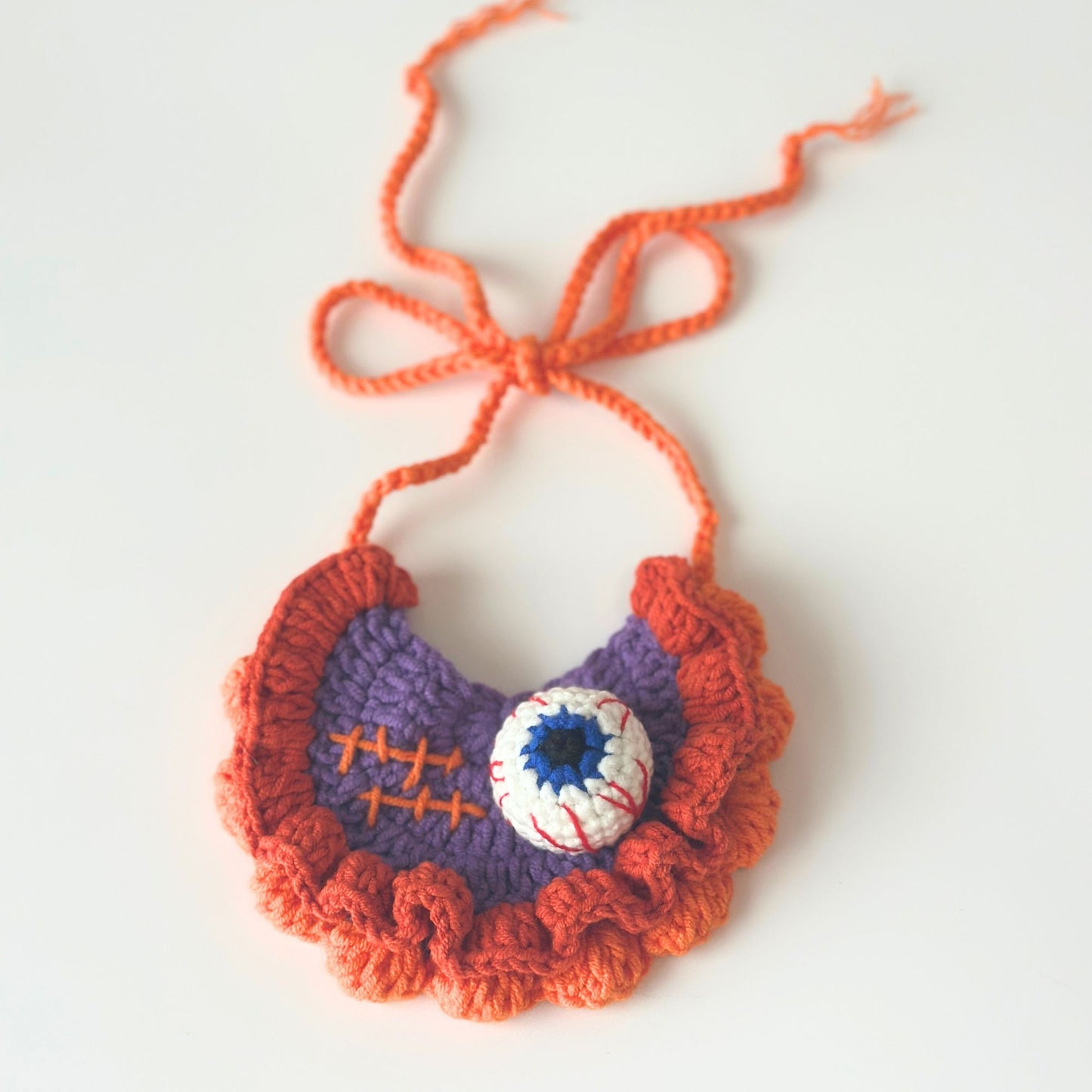 Crocheted bib with orange and purple colors on a white background