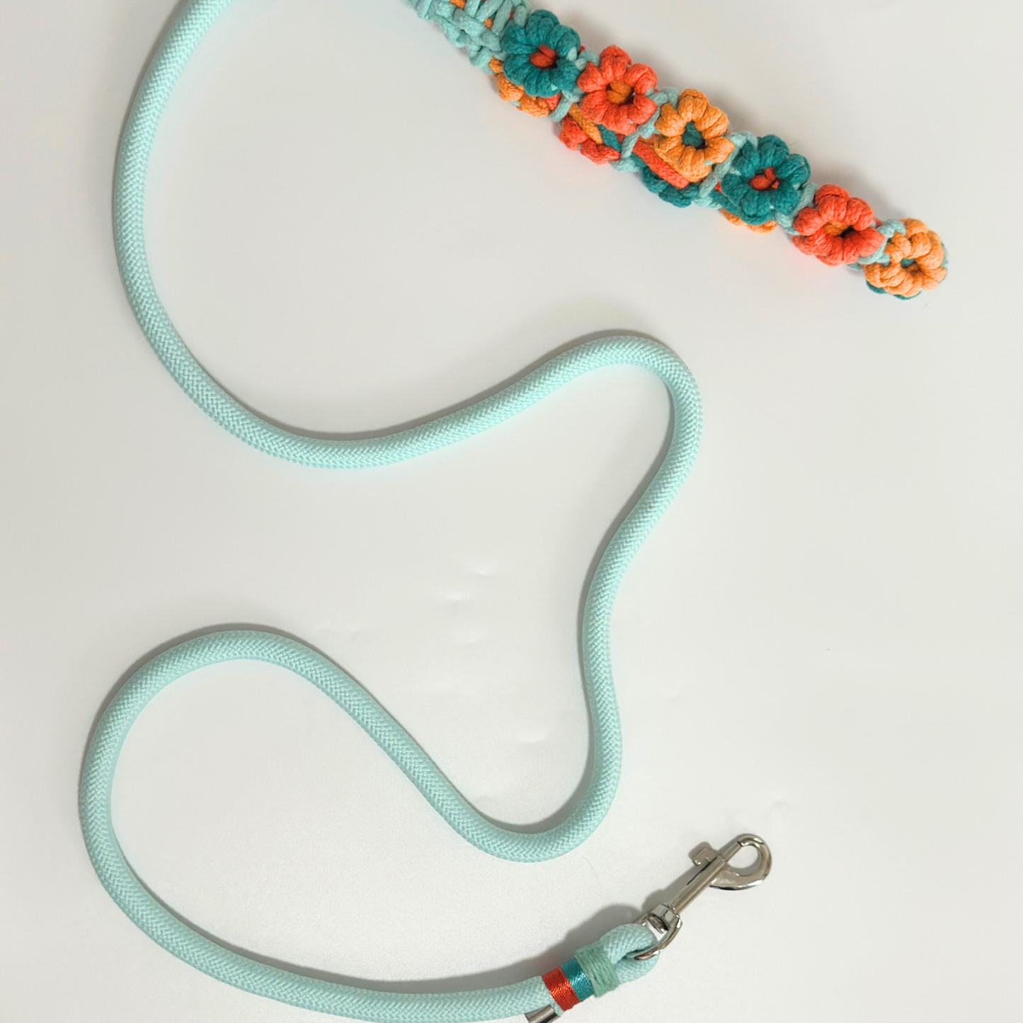 Pet leash product photo showing mint green braided rope construction with decorative hand-crocheted flowers in alternating orange, peach, and teal colors along handle section, sturdy silver metal swivel clip at end