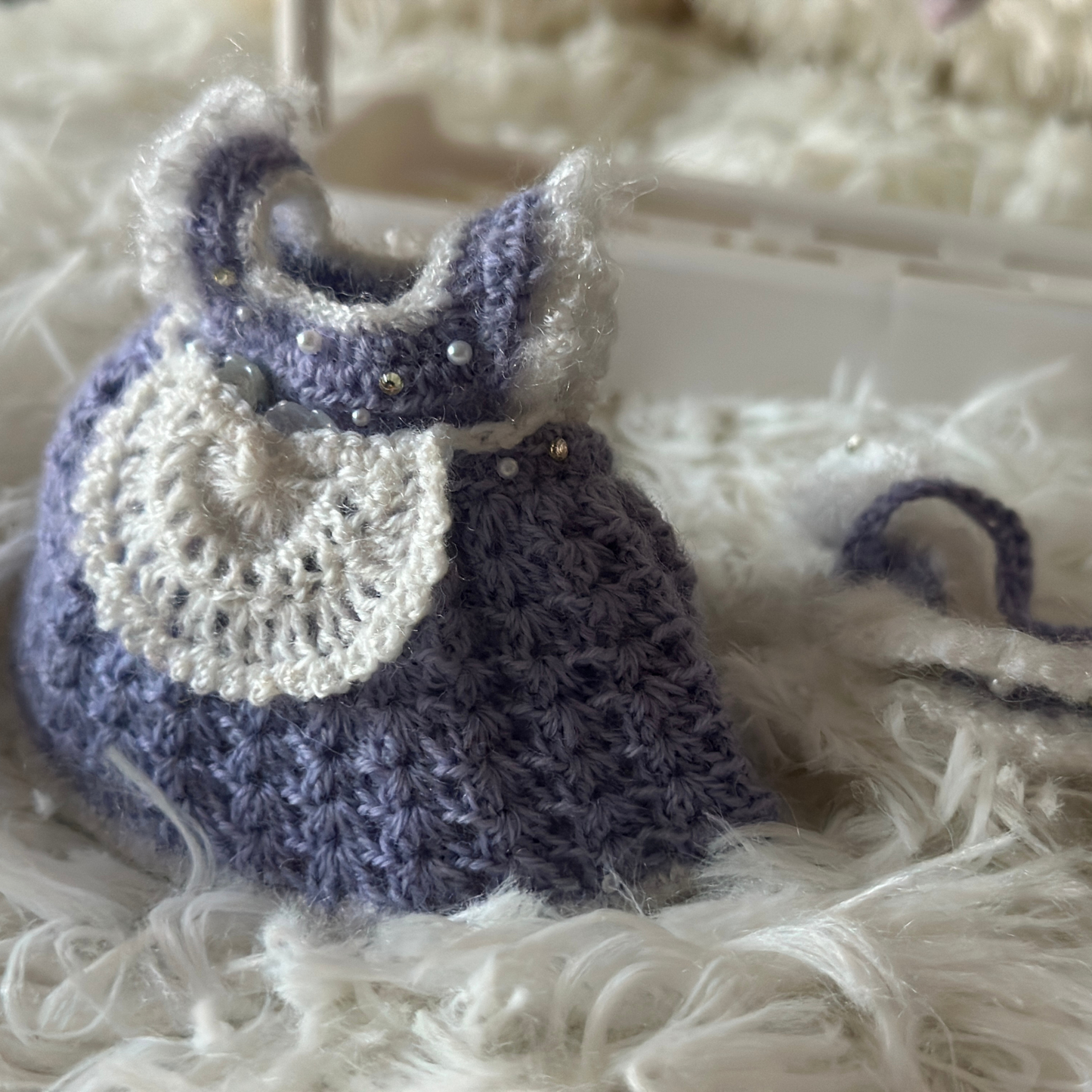 Crocheted labubu dress with white lace collar on a fluffy white surface