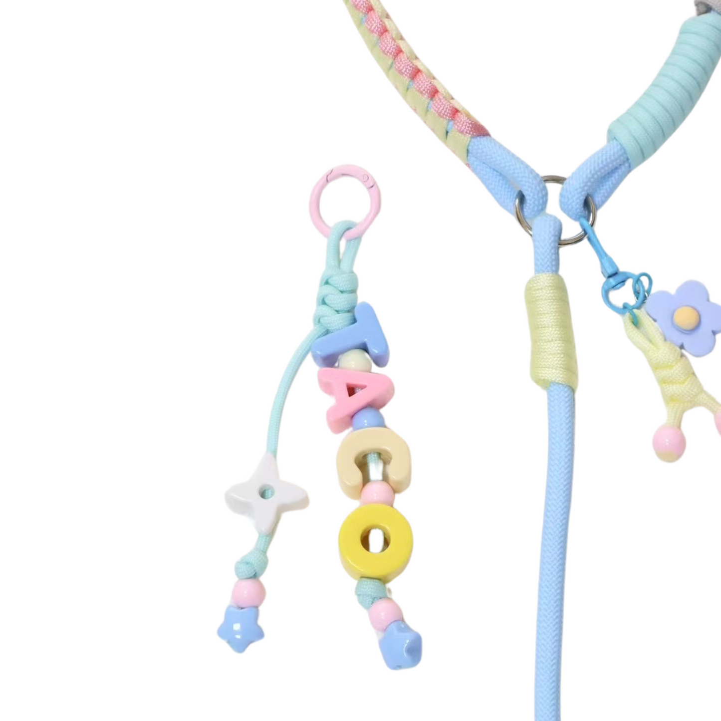 Close-up detail of handmade pastel dog leash showing letter bead charms spelling TACO, flower charm attachment, and colorful wrapped rope collar with braided sections