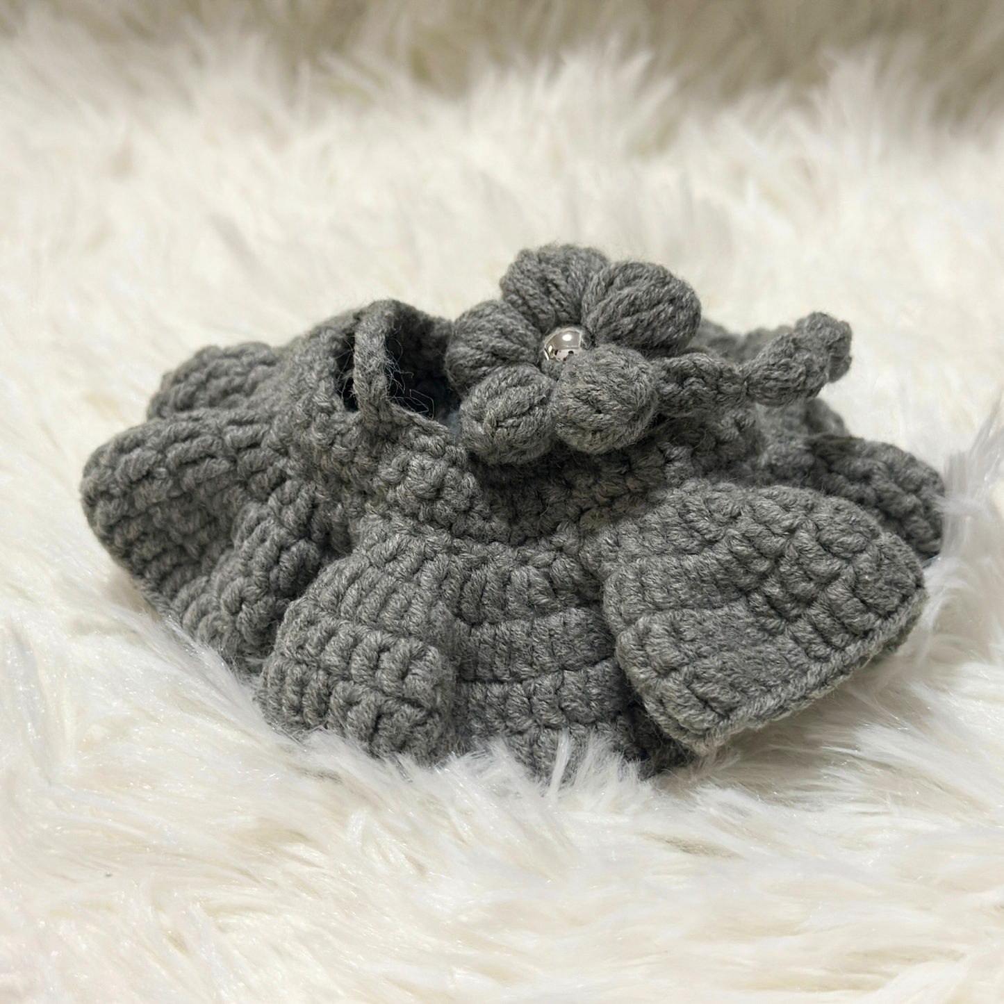Grey crocheted flower accessory for Labbubu doll with pearl center bead and detailed petal construction on white fur background