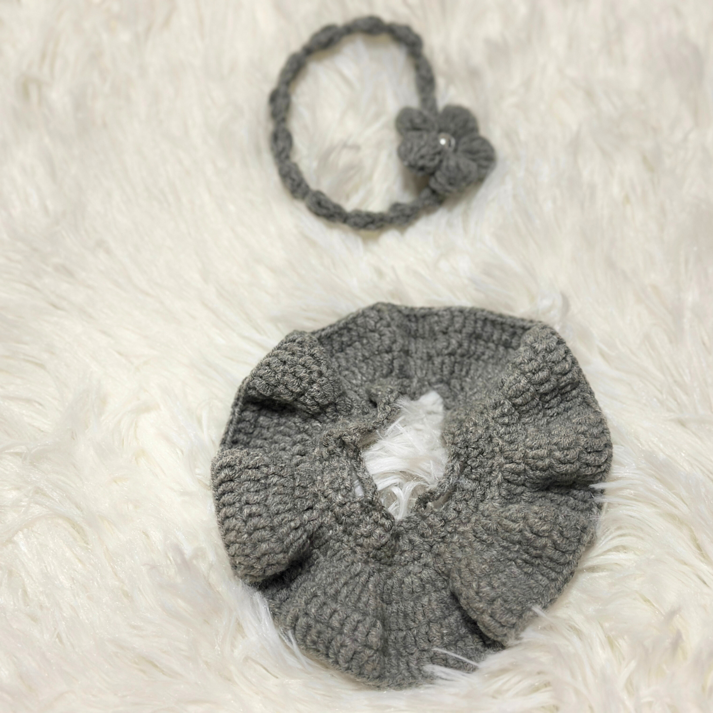 Detailed flat lay view of grey crocheted Labbubu doll dress and matching flower headband on white fur background