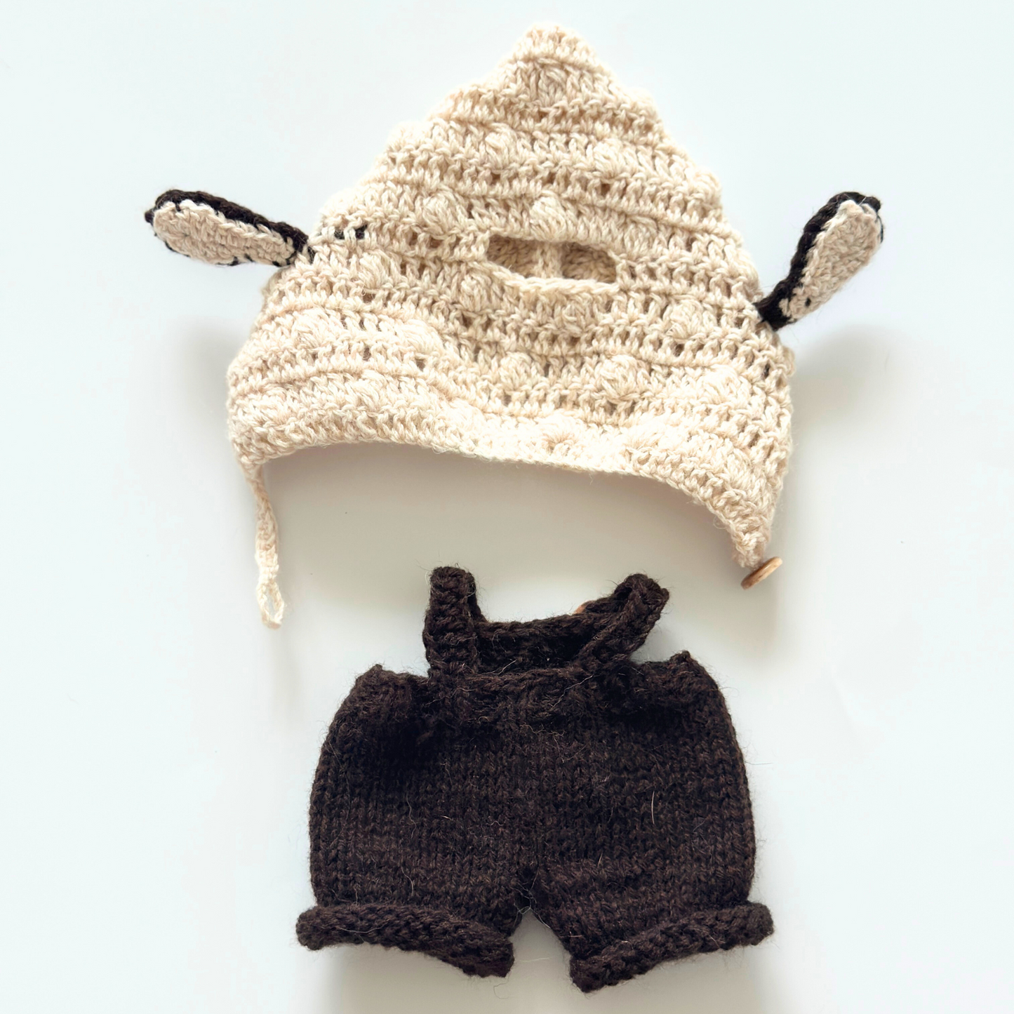 back view Flat lay of Labubu bunny ear hoodie and brown overalls clothing set showing cream knitted hoodie with ears and embroidered popcorn overalls with wooden buttons