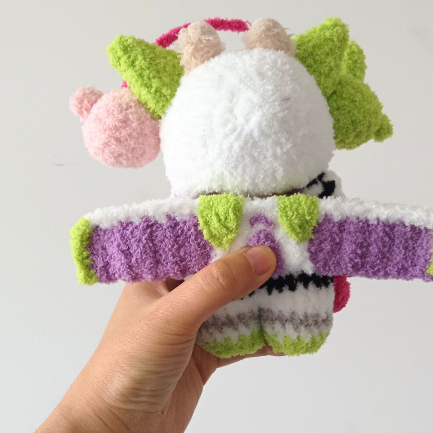 Back view of Labubu doll in Buzz Lightyear costume held in hand, showing purple and white space suit design with colorful toy accessories and detailed costume construction