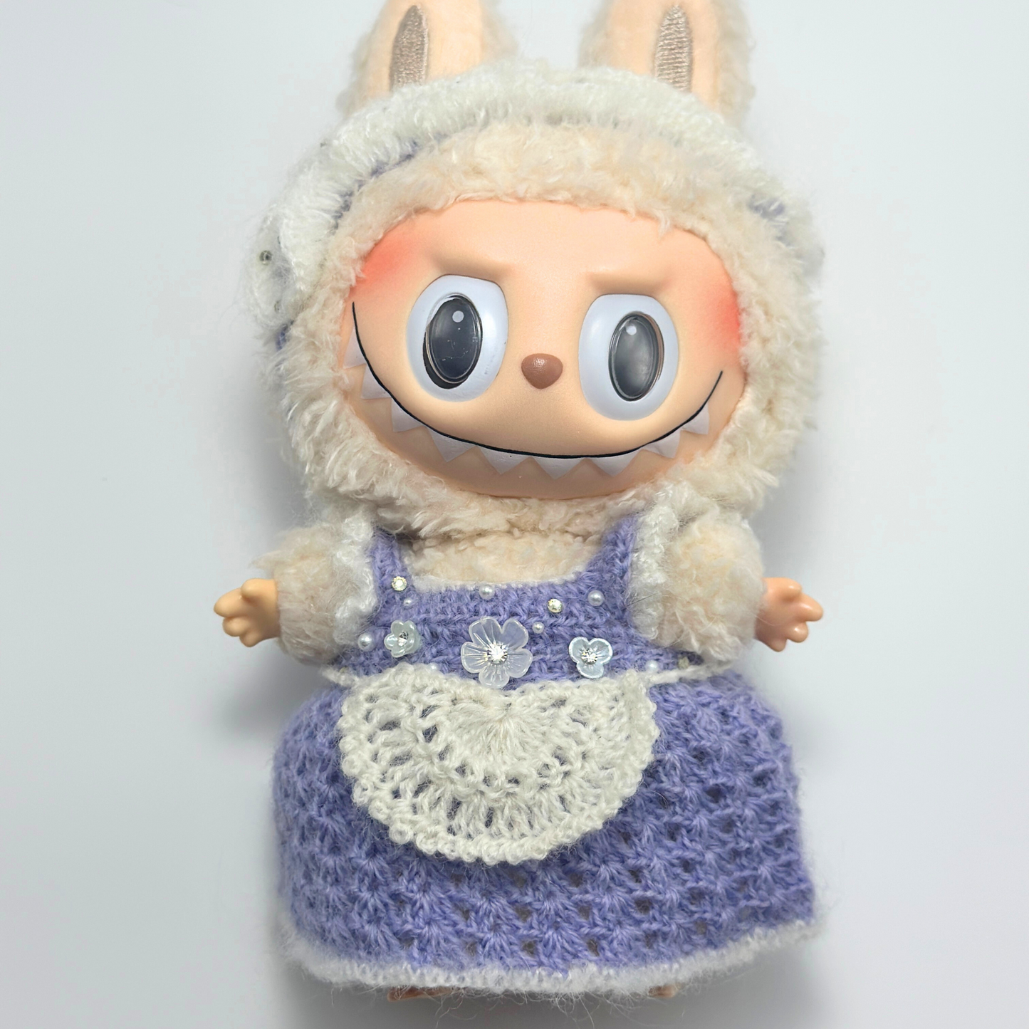 labubu with a knitted outfit on a plain background