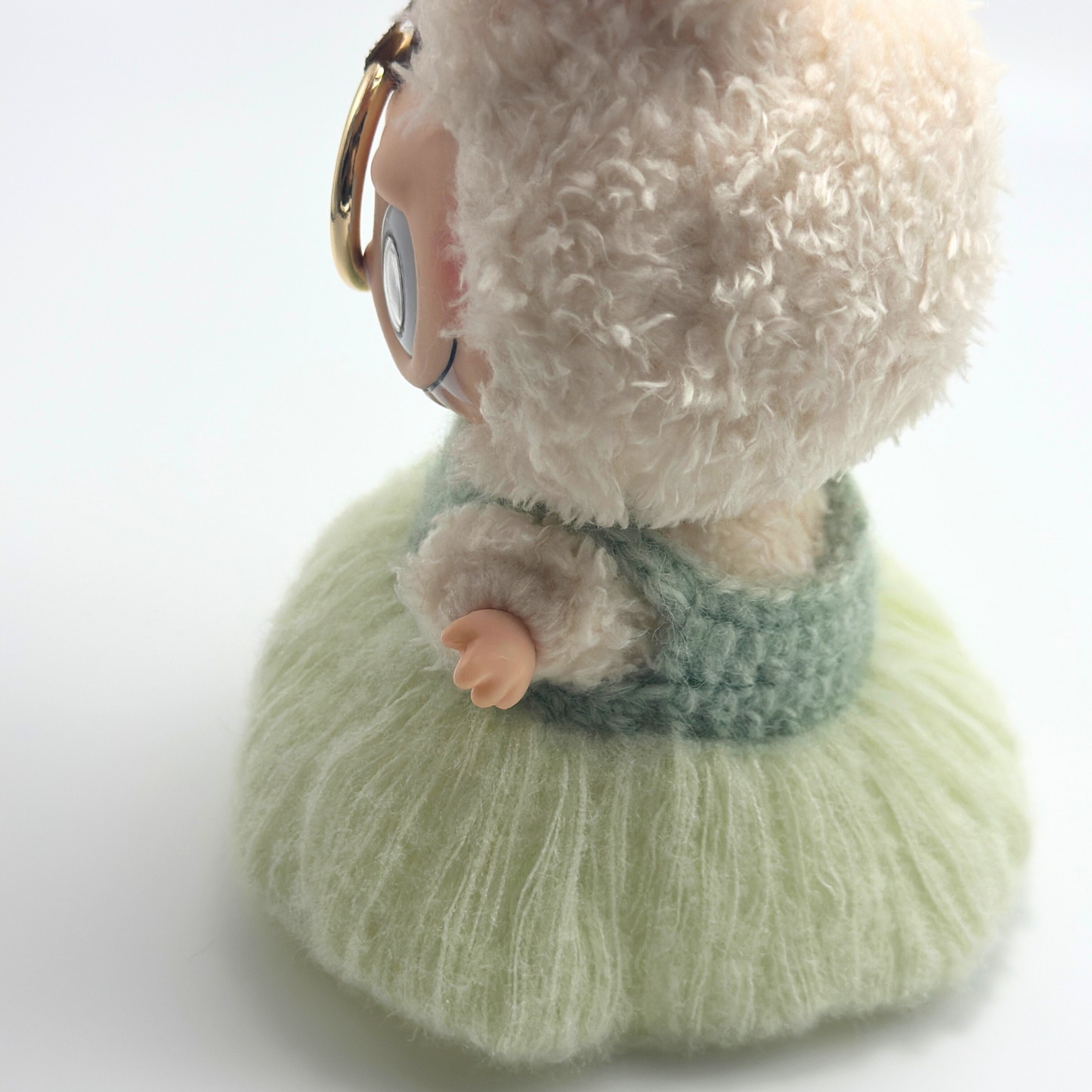 labubu doll with a fluffy white face and green dress on a light background