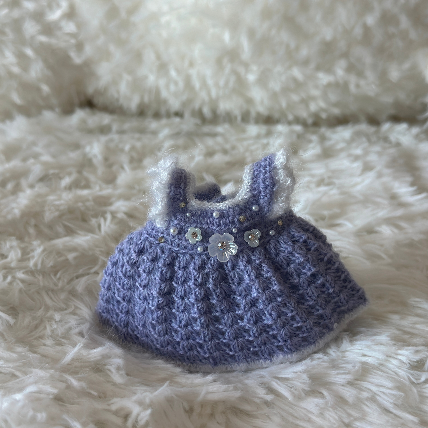 purple knitted dress with white flowers on a fluffy white surface