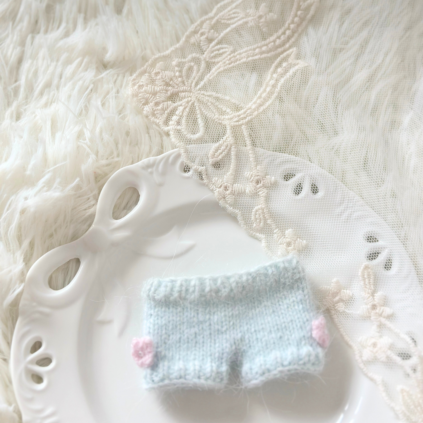 Small blue knitted pantes with pink followers on a white plate