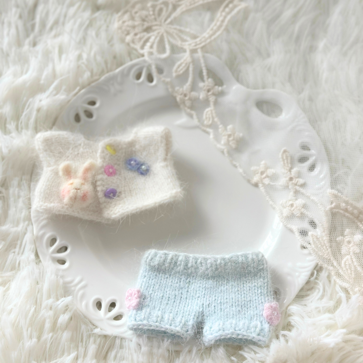 Labubu doll white knitted bunny sweater with colorful buttons and light blue pants laid flat