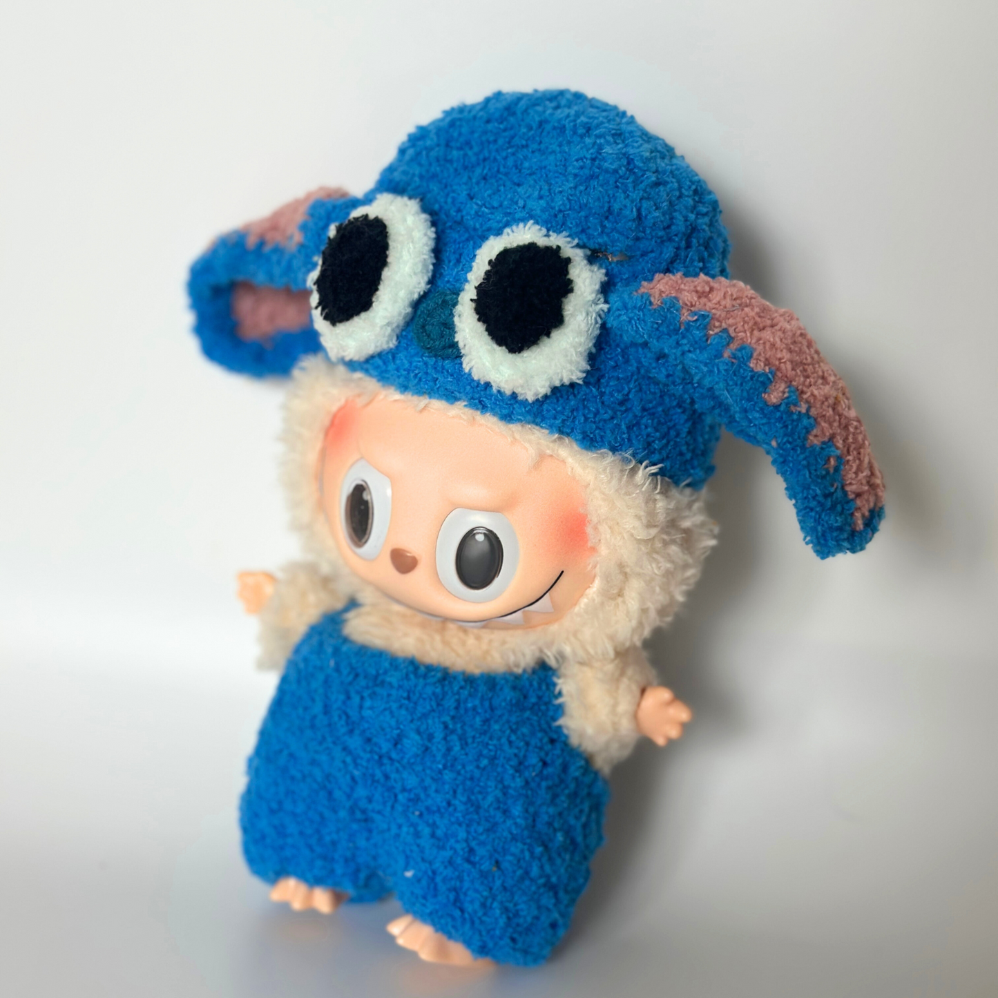 Side view of Labubu doll outfit in blue Stitch style, handmade fluffy costume with big ears and cartoon eyes, cute collectible doll clothes
