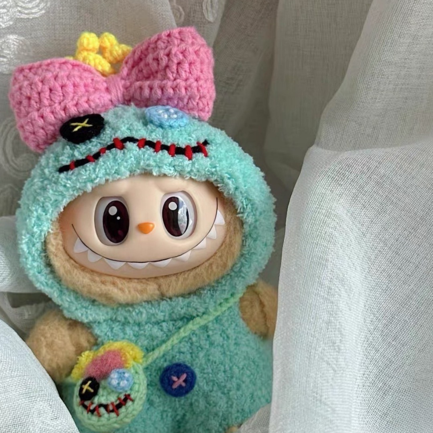 Labubu doll wearing handmade teal crochet Scrump costume with pink bow