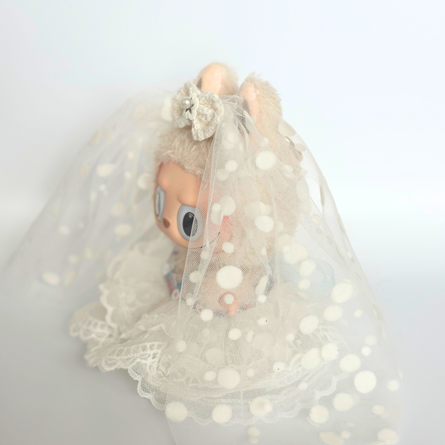 Labubu doll wearing white polka dot wedding dress with bridal veil, flower hair accessories, and layered tulle skirt costume