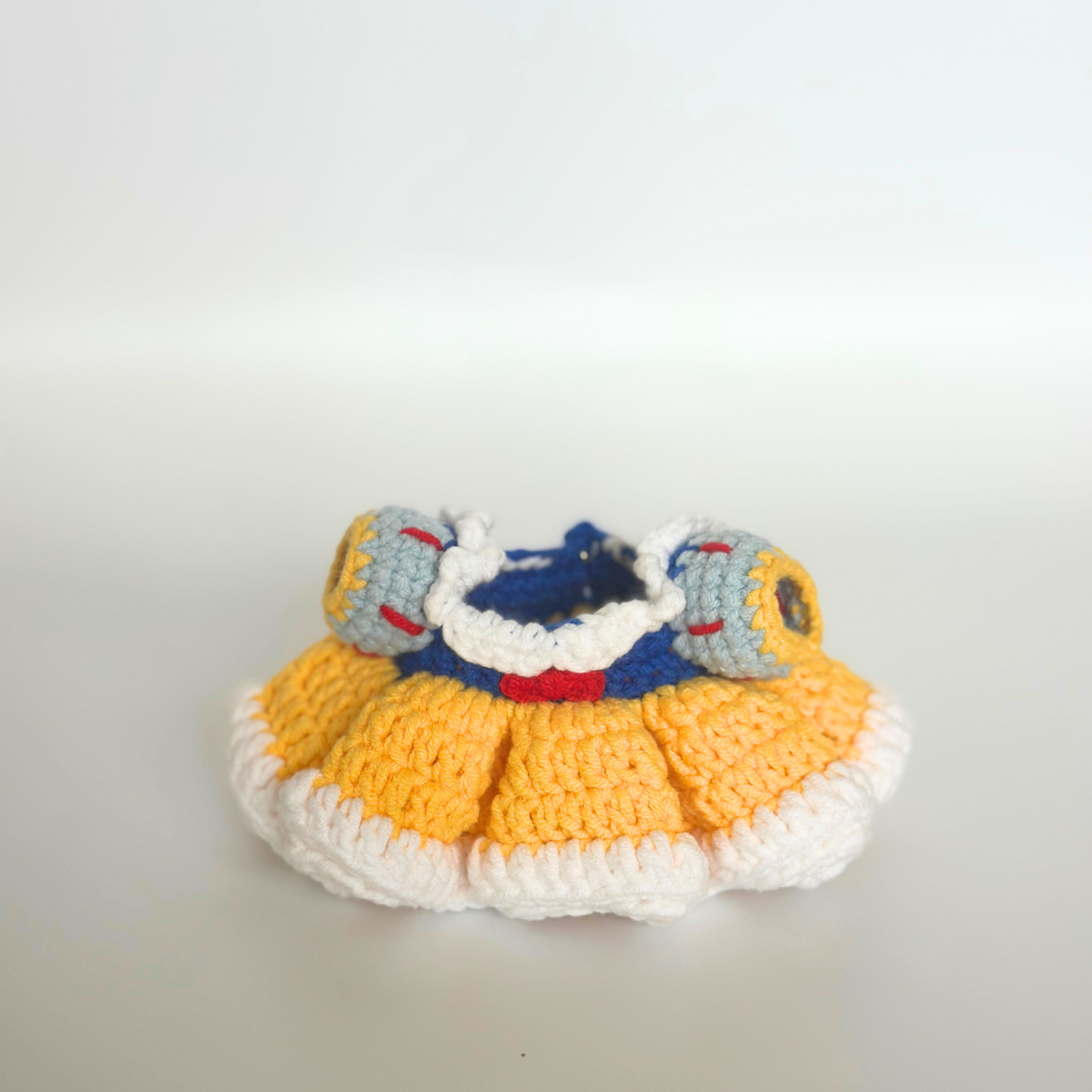 Handmade crocheted Snow White dress costume for Labubu doll featuring blue bodice with white collar, red trim details, puffy gray sleeves with yellow and red accents, layered yellow ruffled skirt, and white base. Perfect dollhouse miniature clothing, collectible doll accessories, DIY crochet craft project for toy enthusiasts and doll collector
