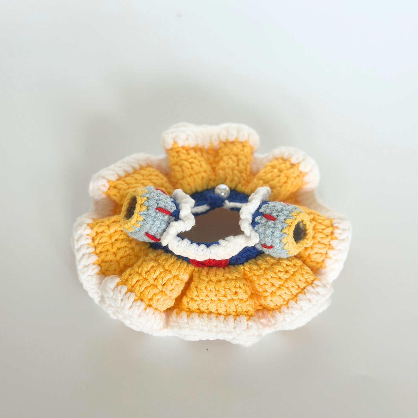 Top-down view of handmade crocheted Snow White costume for Labubu doll showing intricate layered yellow ruffled skirt with white trim, blue bodice with puffy gray sleeves featuring red and yellow details, white collar with decorative stitching. Perfect miniature doll clothing, collectible toy accessories, DIY crochet pattern for doll enthusiasts and handcraft lovers.