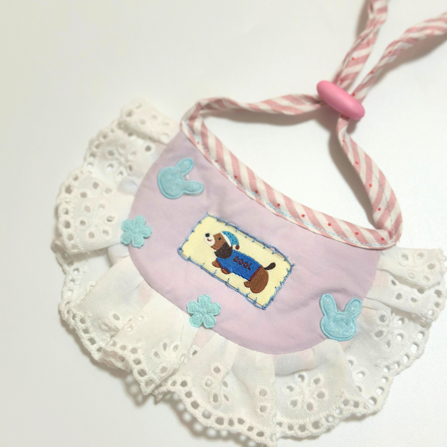 Dog bib bandana flat lay - Pink pet bib with embroidered corgi design, bunny and flower decorations, eyelet lace ruffle, adjustable striped ties for small dogs