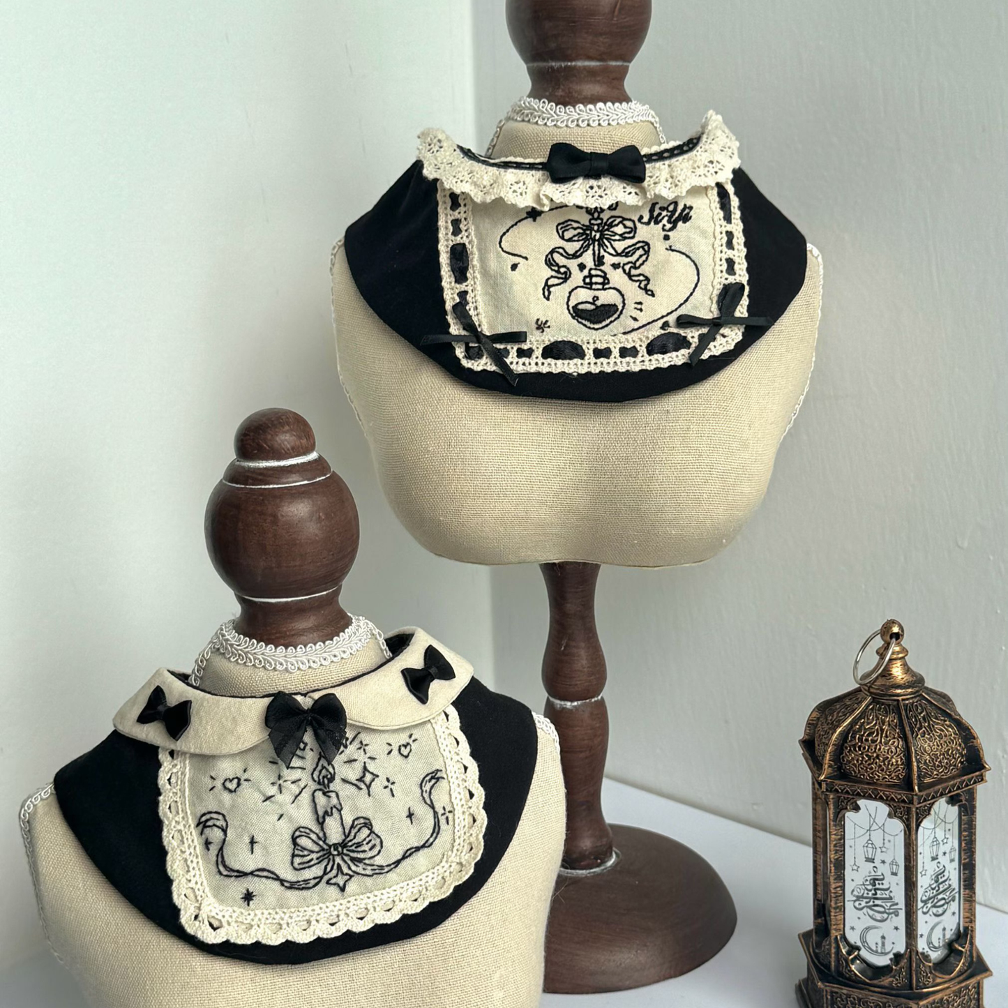Black and white embroidered bandanas on mannequin heads with a decorative lantern in the background.