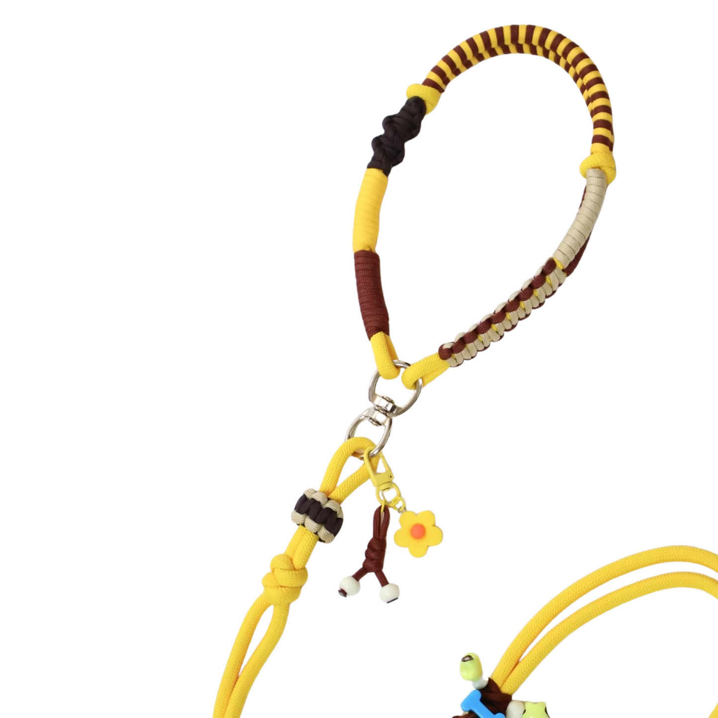 Close-up detail of yellow and brown slip lead dog leash showing paracord weaving with decorative wrapped sections, flower charm and bone charm attachments