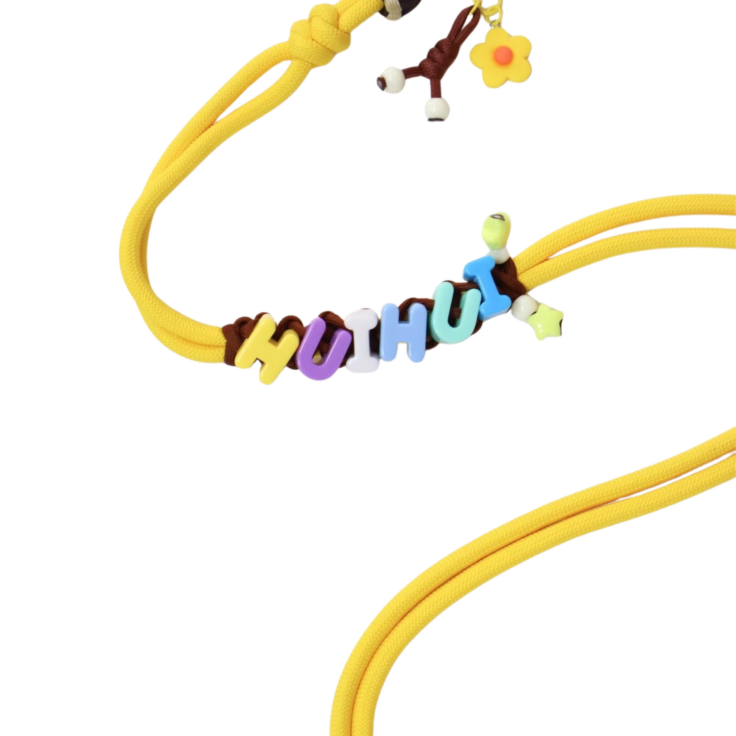 Extreme close-up detail of yellow dog leash showing colorful personalized letter beads spelling name with flower charm and bone charm attachments
