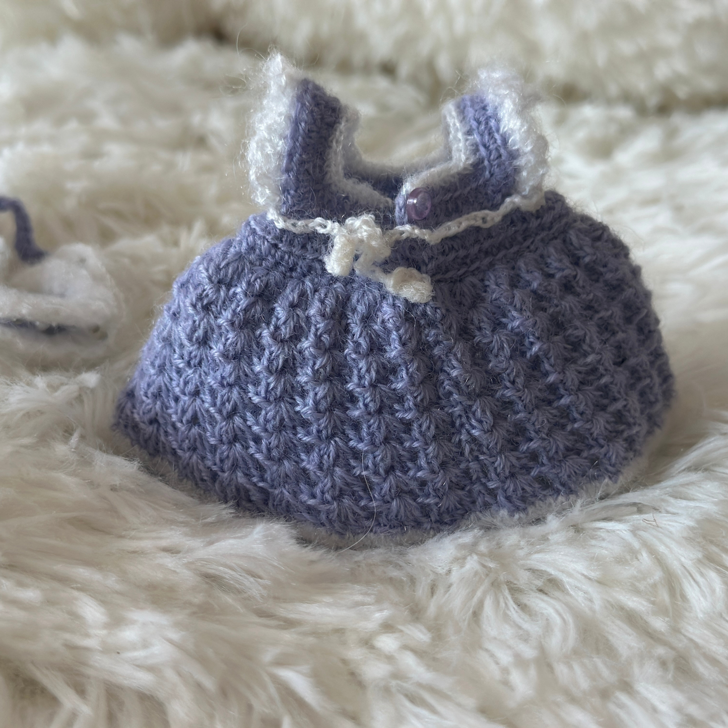 Back view of Knitted labubu dress in blue on a fluffy white surface
