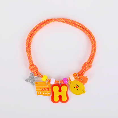Neon orange dog collar  with colorful charms on a light gray background