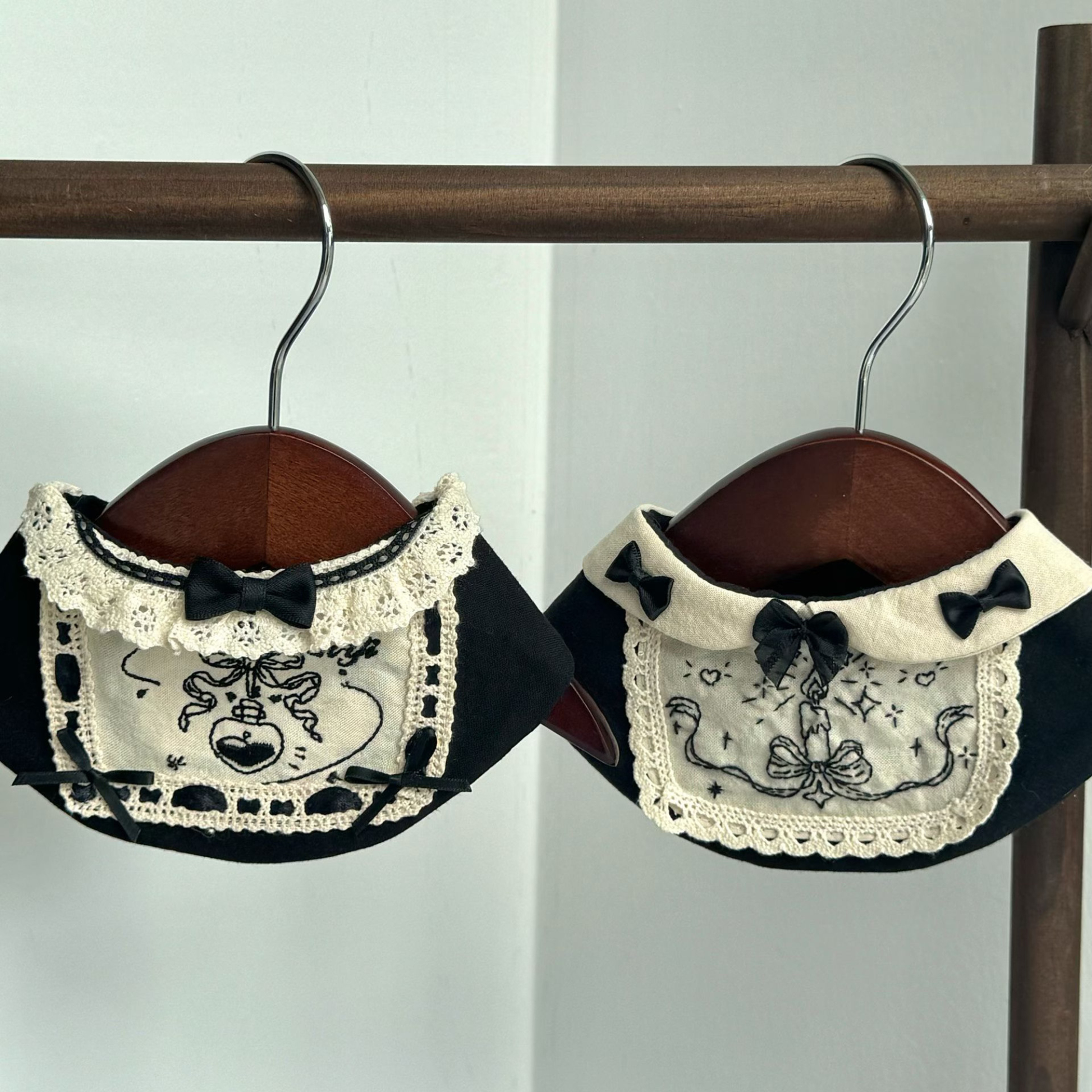 Two lace bandanas with black bows on hangers against a white background