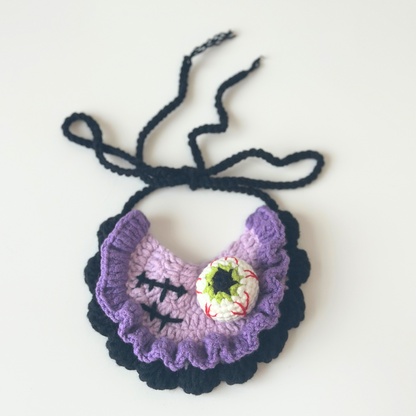 Crocheted purple bib with black straps on a white background