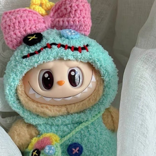 Labubu plush toy dressed in a handcrafted teal crochet outfit inspired by Scrump from Lilo & Stitch, featuring a pink bow headpiece with yellow crown detail, button eye patch, red stitched smile, and matching miniature Scrump accessory