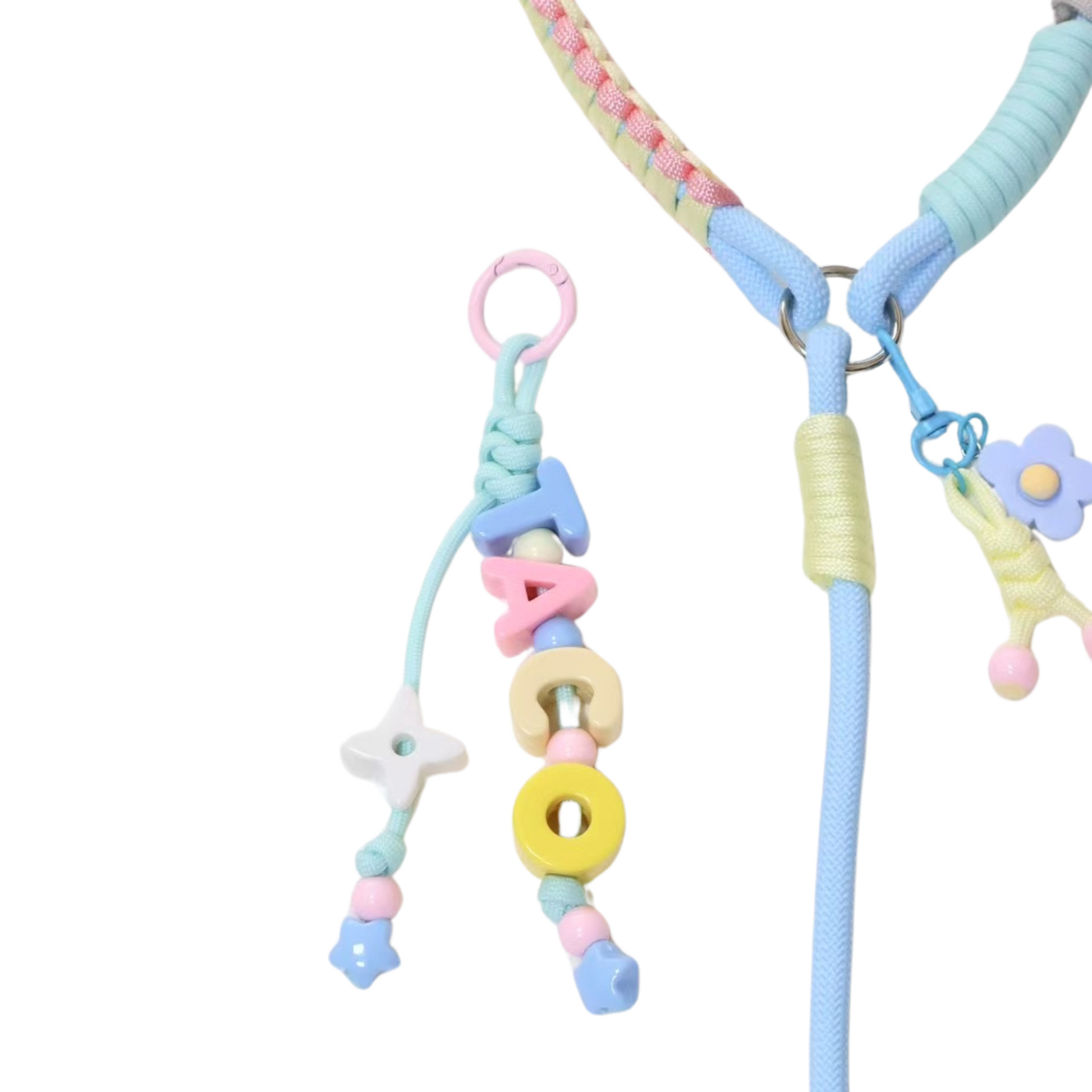 Close-up detail of handmade pastel dog leash showing letter bead charms spelling TACO, flower charm attachment, and colorful wrapped rope collar with braided sections