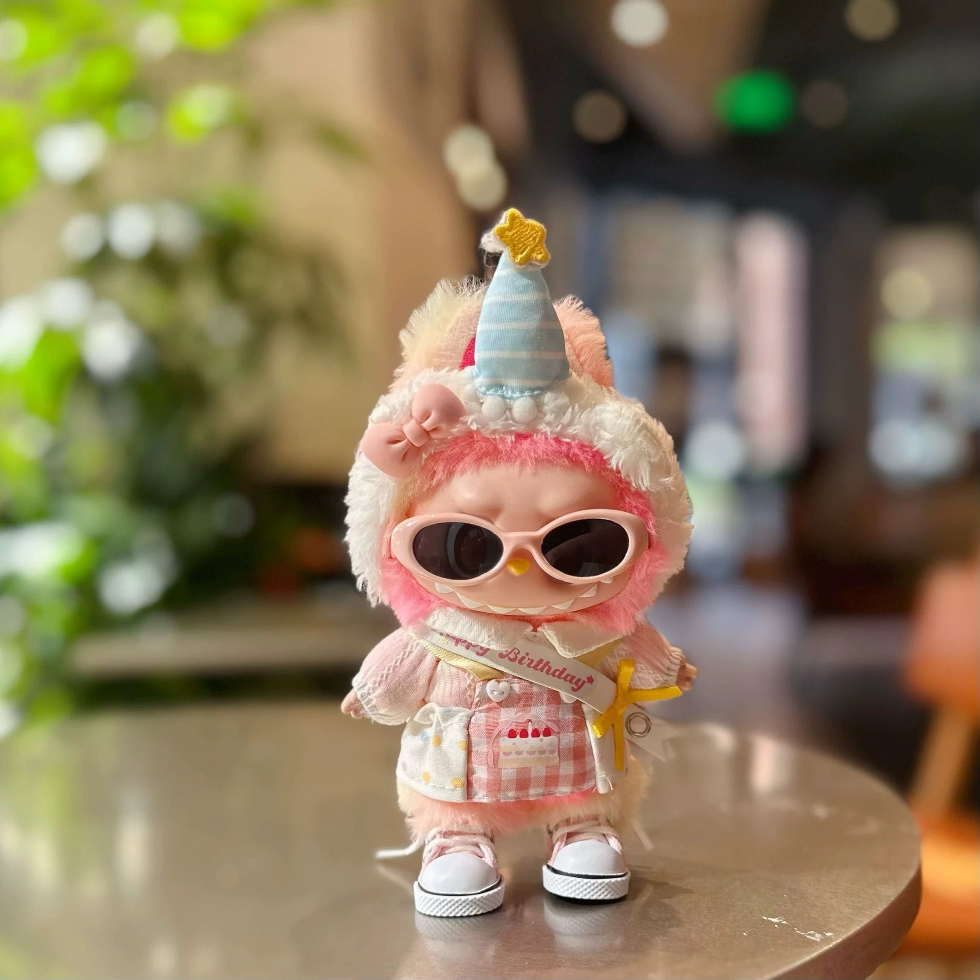 Single Labubu doll wearing birthday celebration costume with pink sunglasses in natural lighting setting