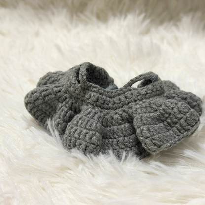 Close-up detail of grey crocheted Labbubu doll skirt showing intricate stitch patterns and fabric texture on white fur background