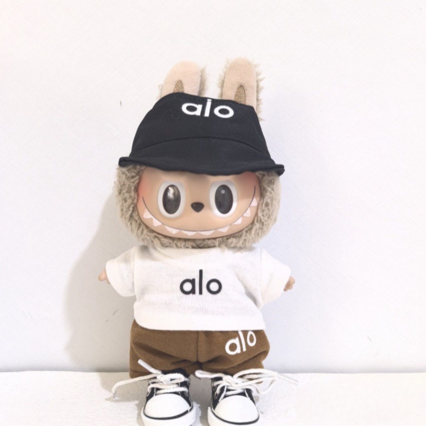 Labubu  doll in alo brown and white athletic outfit with black bucket hat and matching sneakers