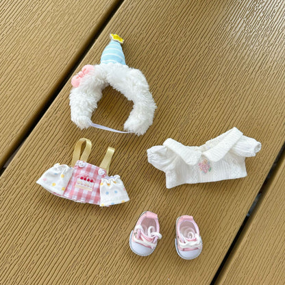 Labubu doll birthday costume accessories laid out separately - fluffy white hat with striped party cap, pink sunglasses, checkered apron with cake print, white ruffled top, and pink sneakers on wooden background