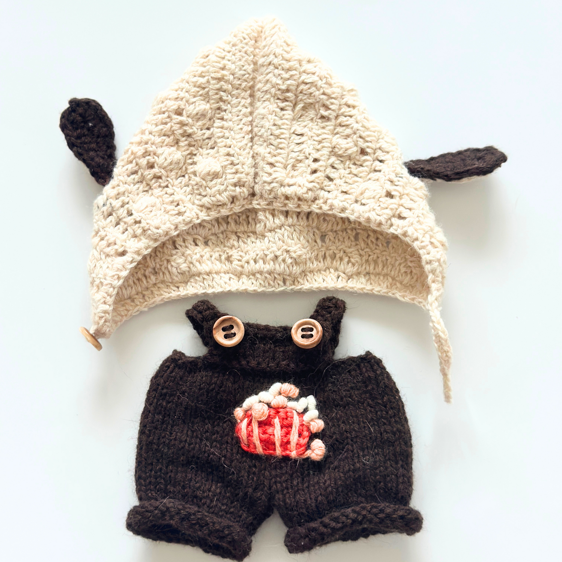 Flat lay of Labubu bunny ear hoodie and brown overalls clothing set showing cream knitted hoodie with ears and embroidered popcorn overalls with wooden buttons