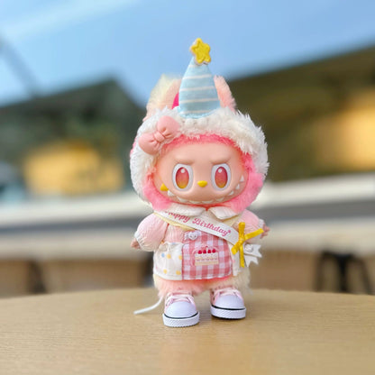 Cute Labubu character in festive pink birthday attire with joyful expression and blurred outdoor background