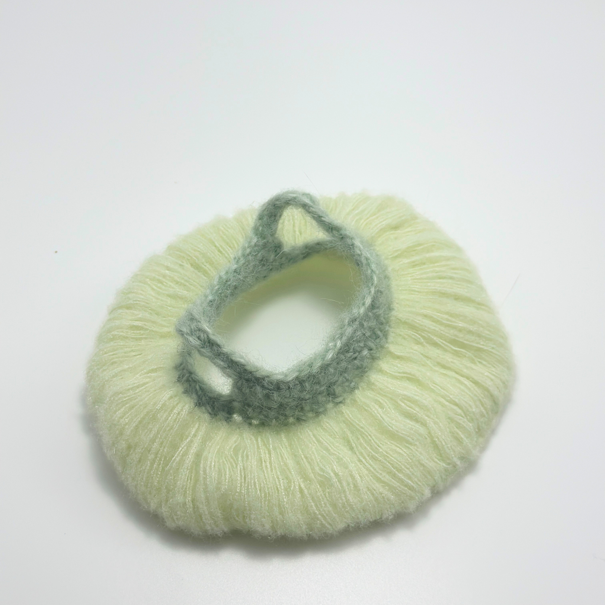 Light green knitted item with a smaller green knitted piece on a white background