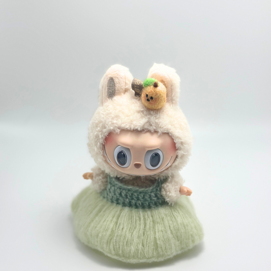 Doll figure with a fluffy white hood and green dress on a light gray background