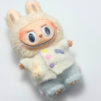 Labubu doll wearing white knitted bunny hoodie sweater with colorful buttons (yellow, pink, purple) and light blue pants - close-up view of handmade doll outfit details