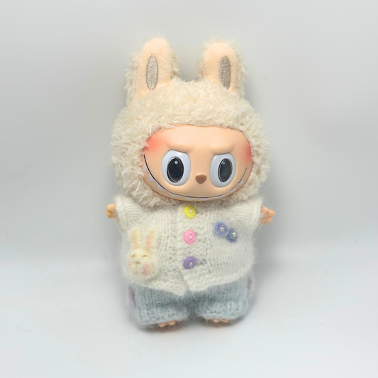 Labubu doll wearing white knitted sweater with bunny hood and colorful buttons (yellow, pink, purple), light blue pants - cute collectible toy outfit