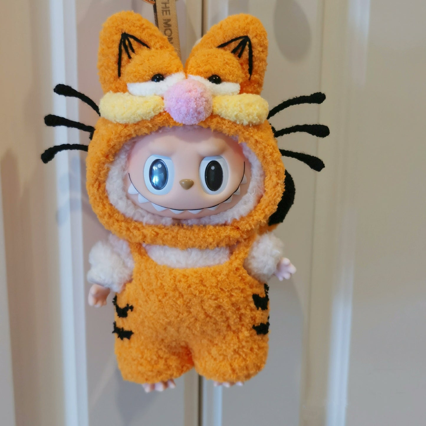 labubu in an orange tiger costume with black stripes on a neutral background