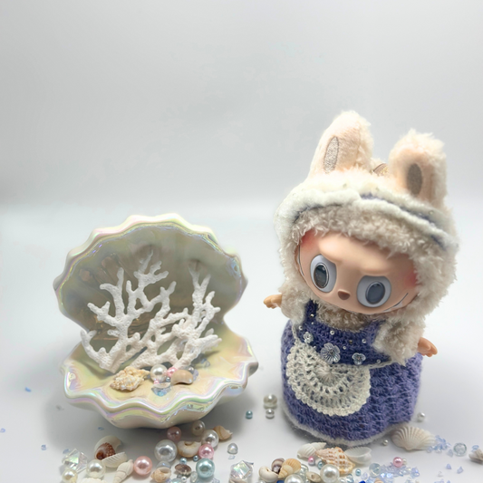 labubu in a knitted outfit with a shell and coral decoration on a light background