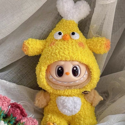 Handcrafted yellow chicken drumstick outfit for Labubu doll featuring fluffy white wing details, orange textured accents, black safety eyes and white belly patch, photographed on delicate white lace with handmade pink crocheted flower decorations