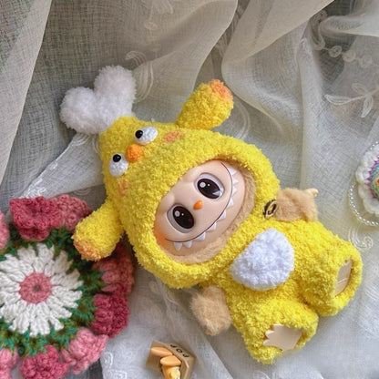 Labubu doll wearing a yellow chicken drumstick costume with white fluffy details, orange beak, and black eyes, displayed on white lace fabric alongside crocheted flowers