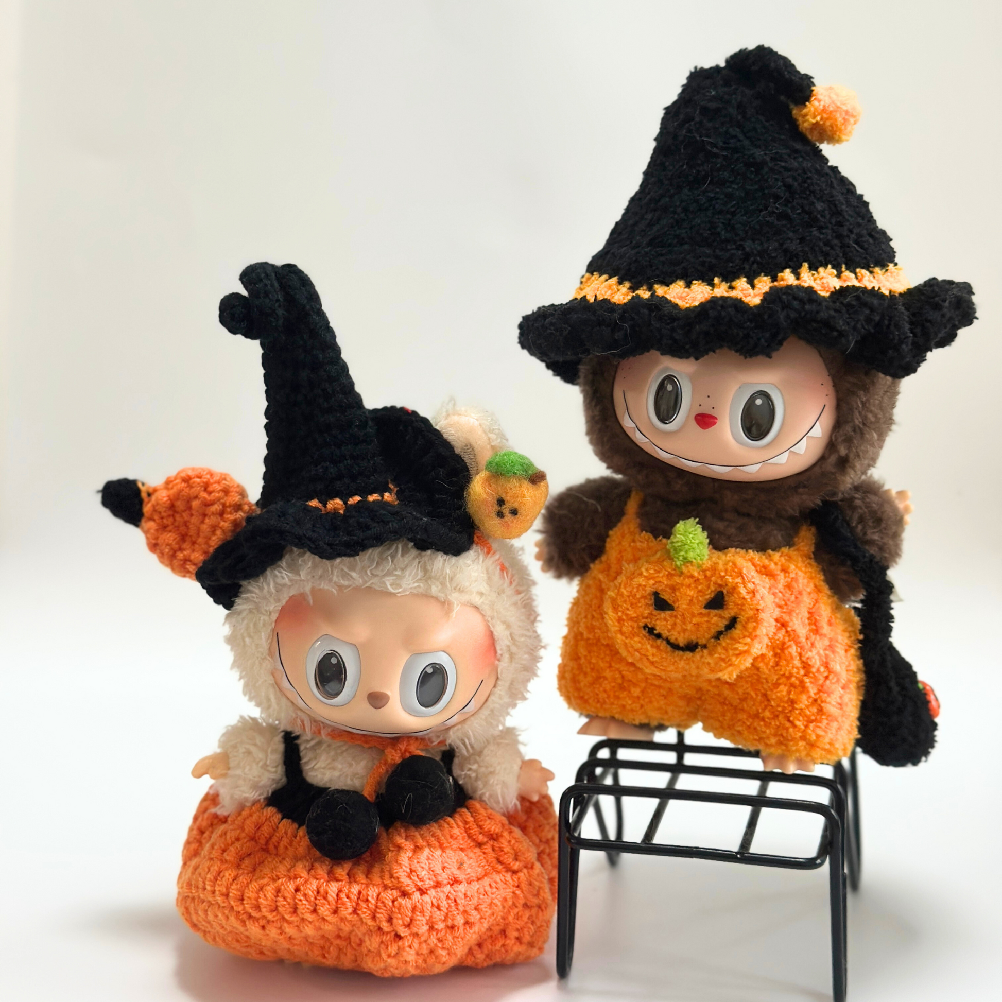 Group photo of handmade crocheted Halloween costumes for Labubu dolls featuring multiple themed outfits: witch costumes with black hats and orange pumpkin jumpsuits, orange pumpkin-shaped standalone costume with witch hat, and various Halloween accessories including trick-or-treat bags. Complete Halloween doll costume collection, seasonal miniature clothing set, collectible toy accessories for Halloween enthusiasts and craft lovers.