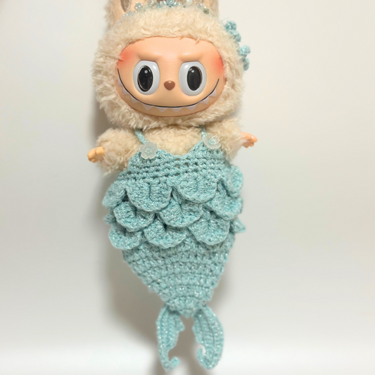 Front view of Labubu doll wearing handmade crocheted mermaid costume in mint green with detailed scale texture, sparkly beaded crown headpiece, shell button shoulder straps, and layered scale pattern bodice. Shows intricate craftsmanship of fantasy-themed doll costume with dimensional scales and decorative crown details, perfect collectible mermaid outfit for doll enthusiasts.