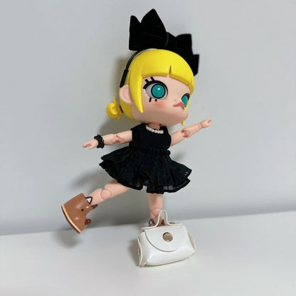 Molly doll wearing a cute black dress with pearl necklace, bow headband, brown shoes, and a white handbag accessory.