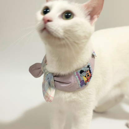 White cat wearing a colorful bandana on a plain background
