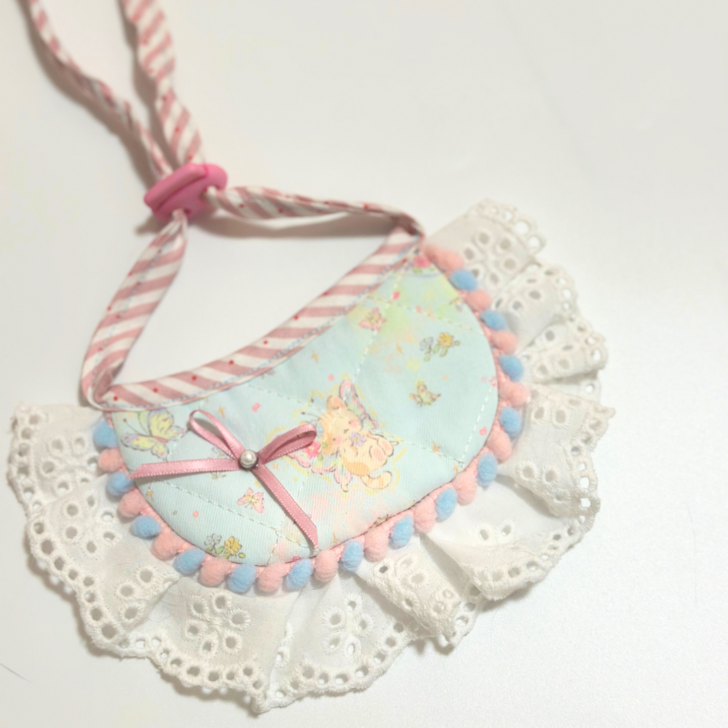 Dog bib with pom-pom trim - Light blue pet bandana bib with bunny print, ribbon bow decoration, eyelet lace ruffle, and adjustable striped ties for small dogs