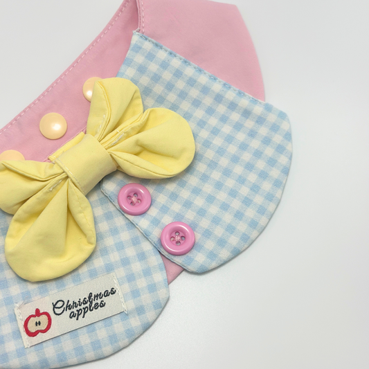 Light blue gingham pet bib with yellow bow tie and pink buttons, featuring "Christmas apples" label with red apple logo - cute pet bandana with checkered pattern